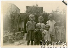 Lato 1944, Warszawa, Generalne Gubernatorstwo.
Grochów, grupa dzieci na podwórku, z przodu rodzeństwo Adam i Elżbieta Jędrych. W tle budynki gospodarcze domów przy ulicy Wzorcowej, gołębnik należący do p. Kurdziela.
Fot. NN, kolekcja Elżbiety Jędrych-Pordes, zbiory Ośrodka KARTA.