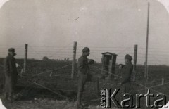 1917, Szczypiorno k/Kalisza, Polska.
Niemiecki obóz dla internowanych jeńców wojennych - polskich legionistów w Szczypiornie. Więźniowie przy ogrodzeniu, za ogrodzeniem wartownik.
Fot. NN, zbiory Ośrodka KARTA, Pogotowie Archiwalne [PAF_004], przekzała Anna Stańczykowska.