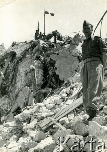 Maj 1944, Monte Cassino, Włochy.
Żołnierz 2 Korpusu Polskiego wśród ruin klasztoru Benedyktynów na Monte Cassino. W tle widać polską i brytyjską flagę.
Fot. Czesław Dobrecki, zbiory Ośrodka KARTA, Pogotowie Archiwalne [PAF_015], przekazał Krzysztof Dobrecki