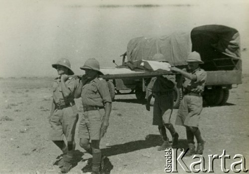 1940-1945, brak miejsca.
Żołnierze niosą ciało zmarłego kolegi na noszach, w tle samochód ciężarowy.
Fot. Czesław Dobrecki, zbiory Ośrodka KARTA, Pogotowie Archiwalne [PAF_015], przekazał Krzysztof Dobrecki