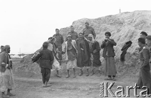 1943, Irak.
Mężczyźni tańczący i grający na instrumentach, wokół stoją polscy żołnierze. W głębi wodoczne namioty obozu wojskowego.
Fot. NN, zbiory Ośrodka KARTA, Pogotowie Archiwalne [PAF_015], przekazał Krzysztof Dobrecki
