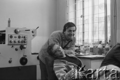 1980-1981, brak miejsca, Polska..
Niezależna drukarnia, stoi Jan Narożniak, na stole z prawej widoczne butelki z utrwalaczem, z lewej stoi maszyna drukarska.
Fot. NN, zbiory Ośrodka KARTA, udostępnił Krzysztof Frydrych.
