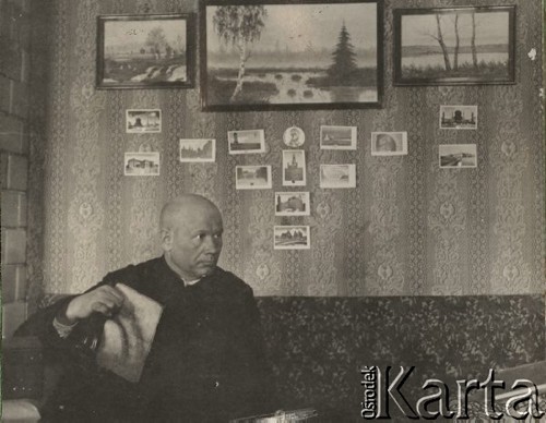 1924-1932, Kosów Poleski, woj. poleskie, Polska.
Ksiądz Feliks Drozdowski, proboszcz parafii w Kosowie Poleskim, siedzący na kanapie w pokoju, na ścianie wiszą pocztówki i obrazy.
Fot. Feliks Drozdowski, zbiory Ośrodka KARTA, Pogotowie Archiwalne [PAF_050], udostępnił Krzysztof Drozdowski