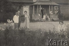 1924-1932, Kosów Poleski, woj. poleskie, Polska.
Grupa osób przed domem, na pierwszym planie trawnik i rosnące na nim kwiaty.
Fot. Feliks Drozdowski, zbiory Ośrodka KARTA, Pogotowie Archiwalne [PAF_050], udostępnił Krzysztof Drozdowski