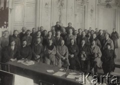 1924-1932, Kosów Poleski, woj. poleskie, Polska.
Grupa osób w zimowych ubraniach we wnętrzu, na pierwszym planie stoi stół, na którym leżą rozłożone dokumenty.
Fot. Feliks Drozdowski, zbiory Ośrodka KARTA, Pogotowie Archiwalne [PAF_050], udostępnił Krzysztof Drozdowski