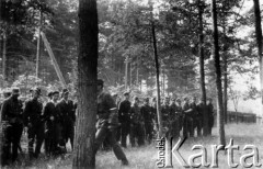 17.07.1944, Czarny Bór, pow. Wileńsko-Trocki.
Oddział partyzancki Bazy z Kedywu Komendy Okręgu Wileńskiego AK na uroczystej zbiórce przed kościołem. Na pierwszym planie, z twarzą zasłoniętą przez drzewo idzie dowódca oddziału plut. pchor. Andrzej Święcicki 