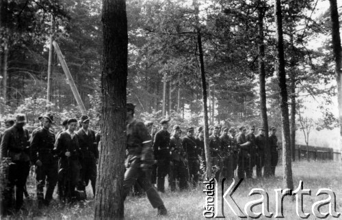 17.07.1944, Czarny Bór, pow. Wileńsko-Trocki.
Oddział partyzancki Bazy z Kedywu Komendy Okręgu Wileńskiego AK na uroczystej zbiórce przed kościołem. Na pierwszym planie, z twarzą zasłoniętą przez drzewo idzie dowódca oddziału plut. pchor. Andrzej Święcicki 