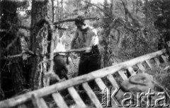 24.07.1944, Puszcza Nacka, okolice Jocz, pow. Wileńsko-Trocki.
Oddział partyzancki Bazy z Kedywu Komendy Okręgu Wileńskiego AK. Biwak nad rzeką Wohubką na przeciwko Jocz. Suczenie ubrań, jedzenie i odpoczynek po wyczerpującym nocnym marszu. Na zdjęciu partyzant oprawiający świnię.
Fot. Zygmunt Zniszczyński, zbiory Ośrodka KARTA, kolekcja BAZY-MIÓD [sygn. 7/16]

