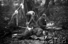 24.07.1944, Puszcza Nacka, okolice Jocz, pow. Wileńsko-Trocki.
Oddział partyzancki Bazy z Kedywu Komendy Okręgu Wileńskiego AK. Biwak nad rzeką Wohubką na przeciwko Jocz. Suczenie ubrań przy ognisku i odsypianie po wyczerpującym nocnym marszu.
Fot. Zygmunt Zniszczyński, zbiory Ośrodka KARTA, kolekcja BAZY-MIÓD [sygn. 7/?]

