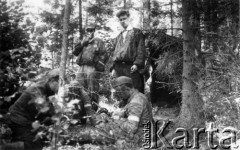Koniec lipca 1944, Puszcza Grodzieńska, pow. Grodno.
Oddział partyzancki Bazy z Kedywu Komendy Okręgu Wileńskiego AK. Czyszczenie broni na biwaku w puszczy. Od lewej stoją: prawdopodobnie Jan Leszczyński 