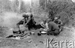 Koniec lipca 1944, Puszcza Grodzieńska, pow. Grodno.
Oddział partyzancki Bazy z Kedywu Komendy Okręgu Wileńskiego AK na biwaku w puszczy. Grupa partyzantów obierających ziemniaki. Od lewej: Dubrowski 