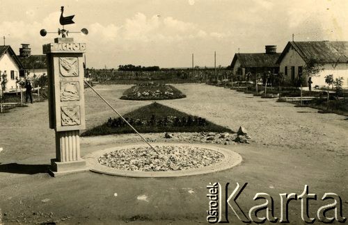 1940, Targu-Jiu, Rumunia.
Obóz dla internowanych żołnierzy Wojska Polskiego, zegar słoneczny w formie kolumny z wyrzeźbionymi symbolami, od dołu: służby uzbrojenia, marynarki wojennej i kwatermistrzostwa. Na zegarze umieszczony wskaźnik kierunku i siły wiatru w formie stylizowanego koguta. Na drugim planie widoczny teren obozu – klomby z posadzonymi drzewami i kwiatami, baraki oraz Aleja Prezydenta RP Władysława Raczkiewicza. 
 Fot. NN, zbiory Ośrodka Karta, album (A-XIII). Zdjęcie ze zbioru ocalonego przez pracownika ambasady PRL w Bukareszcie Jerzego Polakowskiego
   

