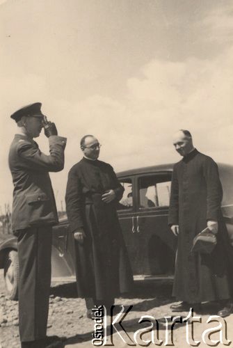 1940, Comisani, Rumunia.
Obóz internowania dla żołnierzy Wojska Polskiego - wizyta zastępcy nuncjusza papieskiego. Na zdjęciu od lewej: polski komendant obozu w Comisani, podpułkownik dypl. pilot Olgierd Tuskiewicz oddający honory wojskowe; z prawej obok samochodu stoi Delegat Nuncjusza Apostolskiego dla Uchodźców Polskich w Rumunii o. Stanisław Skudrzyk; w środku kapelan obozowy ks. Ziółkowski.
 Fot. NN, zbiory Ośrodka Karta, album (A-XII). Zdjęcie ze zbioru ocalonego przez pracownika ambasady PRL w Bukareszcie Jerzego Polakowskiego
   
