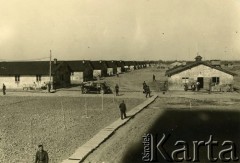 1940, Comisani, Rumunia.
Obóz dla internowanych żołnierzy Wojska Polskiego. Widok od strony baraków oficerskich, po prawej stronie kuchnia i świetlica nr 1, widoczne kładki ułożone na wypadek deszczu.
 Fot. NN, zbiory Ośrodka Karta, album (A-XII). Zdjęcie ze zbioru ocalonego przez pracownika ambasady PRL w Bukareszcie Jerzego Polakowskiego
   
