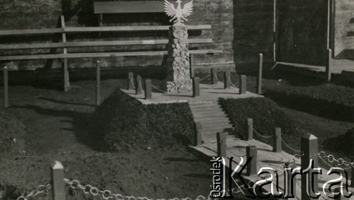 1940, Comisani, Rumunia.
Obóz internowania żołnierzy Wojska Polskiego, pomniczek przed barakiem nr 10 - kopczyk z ziemi, na którym ustawiono niewielką kolumnę z kamieni. Na szczycie kolumny stylizowany orzeł polski. Pomnik jest otoczony ogrodzeniem ustawionym na kopcu, prowadzi do niego wyłożona płytami alejka.
 Fot. NN, zbiory Ośrodka Karta, album (A-XII). Zdjęcie ze zbioru ocalonego przez pracownika ambasady PRL w Bukareszcie Jerzego Polakowskiego
   

