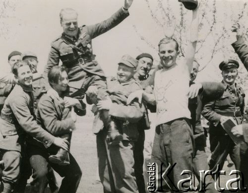 19.03.1940, Comisani, Rumunia.
Obóz dla internowanych żołnierzy Wojska Polskiego. Kpt. Józef Bzowski, kierownik Referatu Kulturalno-Oświatowego, na rękach żołnierzy w dniu swoich imienin. Na zdjęciu m.in. Tadeusz Kustanowicz, Artur Szwarcbrot-Malinowicz, Jerzy Carenko, Władysław Nitoń (w białej koszulce z trupią czaszką).
 Fot. NN, zbiory Ośrodka Karta, album (A-XII). Zdjęcie ze zbioru ocalonego przez pracownika ambasady PRL w Bukareszcie Jerzego Polakowskiego
   
