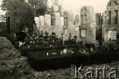 1.11.1940, Targu-Jiu, Rumunia.
 Cmentarz, mogiły żołnierzy polskich zmarłych w obozie internowania. Każda mogiła to nagrobek wykonany z cementu, w który od frontu wmontowano tablicę z danymi zmarłego, powyżej krzyż równoramienny osłonięty łukiem. Wszystkie groby są ozdobione darnią, kwiatami i świecami. Przed mogiłą trzecią i szóstą stoją dzieci  Na dalszym planie stoi odwrócony tyłem żołnierz WP. Od prawej w mogiłach pochowani: Antoni Usarek, strzelec Wojsk Polskich zm. 13.IX.1940; Robert Zwierzyński, kapral Wojsk Polskich zm.12.IX.1940; Teofil Olek, strzelec. Pozostałe tablice inskrypcyjne nieczytelne.
 Fot. NN, zbiory Ośrodka Karta, album (A-XIII). Zdjęcie ze zbioru ocalonego przez pracownika ambasady PRL w Bukareszcie Jerzego Polakowskiego
   
