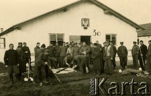 1940, Targu-Jiu, Rumunia.
Obóz internowania żołnierzy Wojska Polskiego, grupa żołnierzy i oficerów WP przed barakiem, na którym widnieje namalowany orzeł wojsk lotniczych wz. 36. Niektórzy ze stojących układają na ziemi mozaikową flagę Jacht Klubu RP. 
 Fot. NN, zbiory Ośrodka Karta, album (A-XIII). Zdjęcie ze zbioru ocalonego przez pracownika ambasady PRL w Bukareszcie Jerzego Polakowskiego
   
