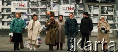 1991, Warszawa, Polska.
Kampania wyborcza przed wyborami parlamentarnymi, przechodnie na tle plakatów kandydatów z Unii Demokratycznej.
Fot. Wojciech Druszcz, zbiory Ośrodka KARTA