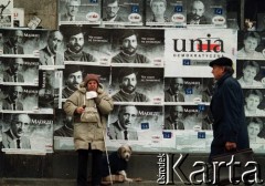 1991, Warszawa, Polska.
Kampania wyborcza przed wyborami parlamentarnymi, żebrząca kobieta na tle plakatów kandydatów Unii Demokratycznej.
Fot. Wojciech Druszcz, zbiory Ośrodka KARTA