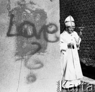 14-15.08.1991, Częstochowa, Warszawa.
Czwarta pielgrzymka papieża Jana Pawła II do Polski. Ojciec Święty wychodzi zza węgła przy klasztorze Paulinów na Jasnej Górze, na ścianie napis: 