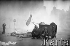 1.05.1982, Gdańsk, Polska.
Stan wojenny. Starcia z ZOMO na gdańskiej Starówce. Na zdjęciu mężczyźni ukrywają sie za śmietnikiem, jeden z nich trzyma flagę.
Fot. Stanisław Składanowski, zbiory Ośrodka KARTA
