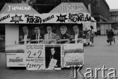 Maj - czerwiec 1989, Kraków, Polska.
Kampania wyborcza przed wyborami do parlamentu. Stoisko na ulicy, na nim widoczne (od góry, od lewej) napisy: J. Hennelowa, J. Rokita, mandat 200 Jan Rokita, mandat 199 Józefa Hennelowa, poniżej portrety: Jana Rokity, Krzysztofa Kozłowskiego, Romana Ciesielskiego, Józefy Hennelowej, Jana Rokity, na dole plakaty z napisami: 
