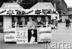 Maj - czerwiec 1989, Kraków, Polska.
Kampania wyborcza przed wyborami do Sejmu. Stoisko na ulicy, na nim widoczne są (od góry, od lewej) napisy: J. Hennelowa, J. Rokita, mandat 200 Jan Rokita, mandat 199 Józefa Hennelowa, poniżej portrety: Jana Rokity, Krzysztofa Kozłowskiego, Romana Ciesielskiego, Józefy Hennelowej, Jana Rokity, na dole plakaty z napisami: 