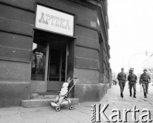 1981, Kraków, Polska.
Dziecko zostawione przed apteką w wózku. Na drugim planie idą funkcjonariusze MO.
Fot. Jerzy Szot, zbiory Ośrodka KARTA