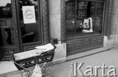 Po 28.05.1981, Kraków, Polska.
Żałoba po śmierci kardynała Stefana Wyszyńskiego. Wózek z dzieckiem stoi przed lokalem, w którego witrynie wystawiono udekorowany kwiatami portret kardynała.
Fot. Piotr Dylik, zbiory Ośrodka KARTA