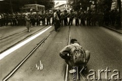 1989, Polska.
Demonstracja Niezależnego Zrzeszenia Studentów pod konsulatem ZSRR. Student zapala świeczki, w głębi kordon milicji.
Fot. Piotr Dylik, zbiory Ośrodka KARTA