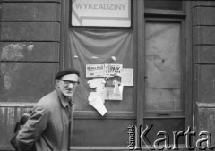 1989 , Kraków, Polska.
Mężczyzna przed okami budynku, na których zawieszono plakaty z hasłami : 