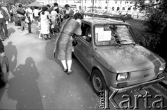 Prawdopodobnie 1989, Kraków, Polska
Kobieta ogląda malucha wystawionego na sprzedaż.
 Fot. Piotr Dylik, zbiory Ośrodka KARTA