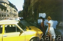 Lata 80., Kraków, Polska.
Kobiety idą chodnikiem przy zamalowanym farą murze prawdopodobnie na Kazimierzu.
Fot. Piotr Dylik, zbiory Ośrodka KARTA