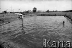 1991, Oświęcim, Polska.
KL Auschwitz Birkenau. Zbiornik na wodę. Kapiący się ludzie. W tle ogrodzenie obozu z wieżami strażniczymi. Z prawej baraki.
Fot. Piotr Dylik, zbiory Ośrodka KARTA