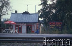 Lata 90., brak miejsca, Polska.
Tablica reklamowa zakładu kołdry przy sklepie spożywczym.
Fot. Piotr Dylik, zbiory Ośrodka KARTA