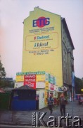 Lata 90., Kraków, Polska.
Mural reklamowy na kamienicy. Poniżej reklamy i szyldy. Dwóch robotników idzie chodnikiem.
Fot. Piotr Dylik, zbiory Ośrodka KARTA