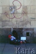 Lata 90., Kraków, Polska.
Żebrząca kobieta z dzieckiem. Na murze stylizowany znak kotwicy - Polski Walczącej.
Fot. Piotr Dylik, zbiory Ośrodka KARTA