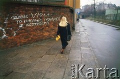 Lata 90., Kraków, Polska.
Kobieta idzie ulicą Siedleckiego. Obok na murze seksistowski napis. 
Fot. Piotr Dylik, zbiory Ośrodka KARTA