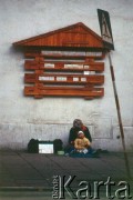 Lata 90., Kraków, Polska.
Żebrząca kobieta z dzieckiem. Na murze tablica na drobne ogłoszenia.
Fot. Piotr Dylik, zbiory Ośrodka KARTA