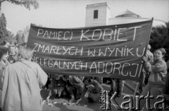 1990, Warszawa, Polska.
Przeciwnicy i przeciwniczki zaostrzenia prawa aborcyjnego demonstrują pod budynkiem Sejmu. Na pierwszym planie (odwrócona plecami) stoi Barbara Labuda. Demonstrujący trzymają transparent z napisem: 