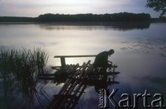 1999, Polska.
Jezioro. Na pomoście żona fotografa, Katarzyna Dylik, nabiera wodę do butelki. 
Fot. Piotr Dylik, zbiory Ośrodka KARTA
