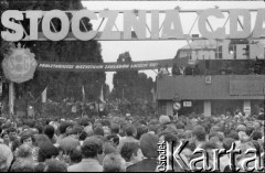 Sierpień 1980, Gdańsk, Polska.
Strajk w Stoczni Gdańskiej im. Lenina. Tłum przed bramą nr 2, z prawej widoczna jedna z dwóch tablic z wypisaną odręcznie listą 21 postulatów strajkujących.
Fot. Jan Juchniewicz, zbiory Ośrodka KARTA