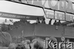 Sierpień 1980, Gdańsk, Polska.
Strajk w Stoczni Gdańskiej im. Lenina. Tłum przed bramą nr 2, z prawej widoczna jedna z dwóch tablic z wypisaną odręcznie listą 21 postulatów strajkujących.
Fot. Jan Juchniewicz, zbiory Ośrodka KARTA