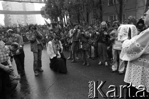 Sierpień 1980, Gdańsk, Polska.
Strajk w Stoczni Gdańskiej im. Lenina. Msza święta na terenie stoczni. Fotoreporterzy robią zdjęcia, przed księdzem trzymającym kielich mszalny z hostią klęczy ksiądz Henryk Jankowski.
Fot. Witold Górka, zbiory Ośrodka KARTA