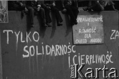 Sierpień 1980, Gdańsk, Polska.
Strajk w Stoczni Gdańskiej im. Lenina. Na murze otaczającym stocznię siedzą strajkujący, poniżej hasła: 