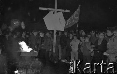 12.12.1988, Wrocław, Polska.
Happening Pomarańczowej Alternatywy na ulicy Świdnickiej - Wigilia Stanu Wojennego. Uczestnicy przed płonącymi tekturowymi czołgami i tarczami ZOMO. Jeden z uczestników trzyma krzyż z mapą Polski. Inny unosi transparent: pomścimy wujka i ciocię.
Fot. Mieczysław Michalak, zbiory Ośrodka KARTA.