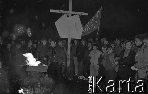 12.12.1988, Wrocław, Polska.
Happening Pomarańczowej Alternatywy na ulicy Świdnickiej - Wigilia Stanu Wojennego. Uczestnicy przed płonącymi tekturowymi czołgami i tarczami ZOMO. Jeden z uczestników trzyma krzyż z mapą Polski. Inny unosi transparent: pomścimy wujka i ciocię.
Fot. Mieczysław Michalak, zbiory Ośrodka KARTA.