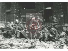 Sierpień lub wrzesień 1944, Warszawa, Polska.
Powstańcy ze Śródmieścia pozują do pamiątkowego zdjęcia. Za nimi widoczny zniszczony budynek dawnego Towarzystwa Ubezpieczeń 