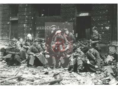 Sierpień lub wrzesień 1944, Warszawa, Polska.
Powstańcy ze Śródmieścia pozują do pamiątkowego zdjęcia. Za nimi widoczny zniszczony budynek dawnego Towarzystwa Ubezpieczeń 